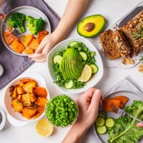 Healthy vegan food lunch, top view. Vegetarian dinner table, people eat healthy food. Salad, sweet potato, vegan cake, vegetables on a white background.